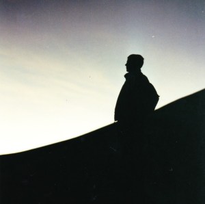 silhouette of man standing on side of mountain at dawn