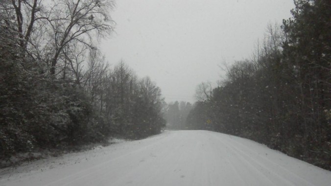 snow falling and blanketing the road